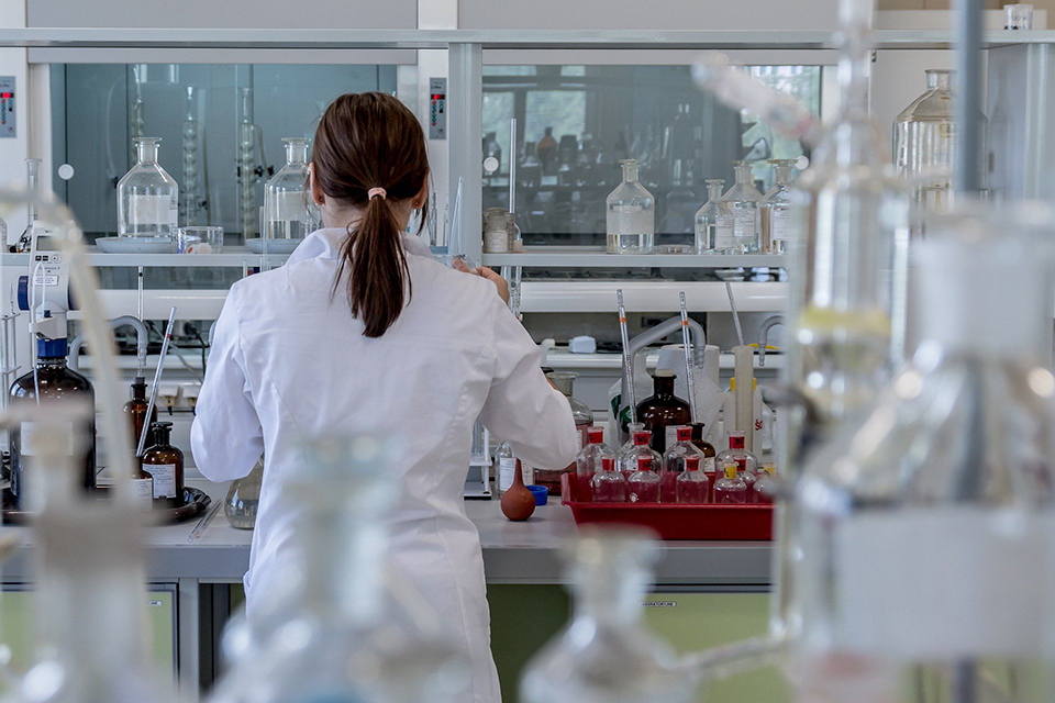 Ein Labor mit einer arbeitenden Wissenschaftlerin, die dir den Rücken zukehrt.